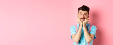 Aptal genç adam ellerini kaldırıp yukarı bakıyor, bir şeyin hayalini kuruyor, pembe arka planda bir şeyler canlandırıyor..