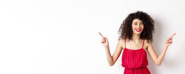 Kıvırcık saçlı, kırmızı dudaklı, gülümseyen beyaz dişli, iki tarafı gösteren, reklamları bir kenara bırakıp beyaz arka planda duran mutlu bir kadın..