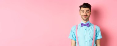 Gülümseyen beyaz adam heyecanlı görünüyor, şık papyon ve gömlek içinde romantik randevu için, pembe arka plan.