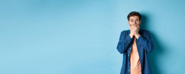 Şok olmuş, ağzı kapalı ve nefes nefese kalmış bir adam pusuya düşürülmüş. Mavi arka planda duran korkunç bir şeye tanık olmuş..