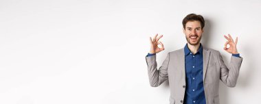 İyi seçim. Takım elbiseli gülümseyen işadamı iyi işaretler gösteriyor ve mutlu görünüyor. İyi bir anlaşma öneriyor. Seçiminizi onaylıyor ve onaylıyor..