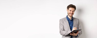 Takım elbiseli, gülümseyen erkek yönetici. Panoya yazı yazıyor. Ofis toplantısında notlar alıyor..