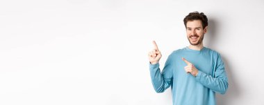 Fotokopi alanında reklam gösteren neşeli sakallı adam sol üst köşedeki logoyu işaret ediyor ve gülümsüyor, beyaz arka planın üzerinde duruyor..