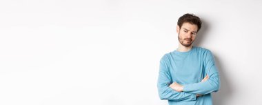 Kararsız ve düşünceli sakallı bir adam düşünceli, dalgın dalgın bakıyor ve seçim yapıyor, beyaz arka planda duruyor..