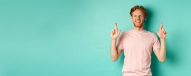 İyimser bir adam, kızıl saçlı ve sakallı, şans dilemek için şans diliyor ve kameraya umutla bakıyor, bir dilek diliyor, nane arkaplan başında duruyor..