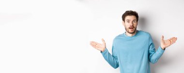 - İnanılmaz. İnançsızlıkla bakan, ellerini yana açmış, etkilenmiş, beyaz arka planda duran genç adam..