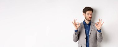 - Çok iyi. Takım elbiseli yakışıklı adam göz kırpıyor ve tamam işareti gösteriyor. Kıyafetini beğeniyor ve onaylıyor. Seçimini övüyor..