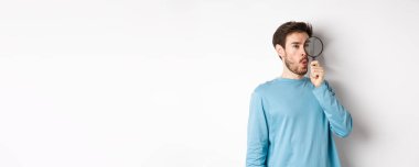 Meraklı adam sağ logodaki büyüteçten bakıp 