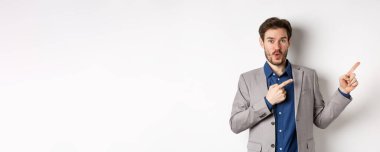 Heyecanlı, beyaz takım elbiseli beyaz iş adamı logoyu işaret ediyor, 