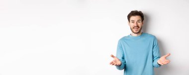 Yakışıklı genç adam senin için mutlu hissediyor, kameraya el kaldırıyor ve iyi işi övüyor, tebrik ediyor, beyaz arka planda duruyor..