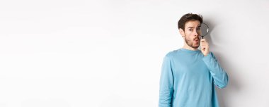 Şaşırmış bir adam bir şey buldu. Büyüteçten bakıp şaşkın şaşkın baktı. Beyaz arka planda duruyordu..