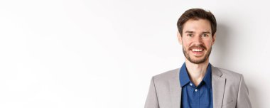 Takım elbiseli, gülen, gülümseyen, beyaz arka planda duran mutlu sakallı adamın yakın çekimi..