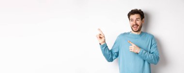 Heyecanlı sakallı adam özel teklifi kontrol ediyor, mutlu yüzle reklamlara bakıyor, beyaz arka planda duruyor..