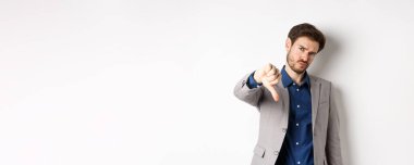 Olumsuz duygular. Hayal kırıklığına uğramış işadamı kaşlarını çatıyor, ürünleri onaylamıyor, kötü bir şeyden hoşlanmıyor, beyaz arka planda geziniyor..