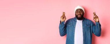 Genç Afro-Amerikan bir adamın mızmızlanması, tanrıya yalvarması, dua etmesi ve ağlaması, pembe arka planda dikilmesi..