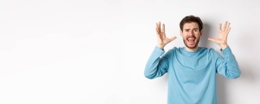 Korkmuş genç bir adamın el sıkışması, çığlık atması, kameraya bağırması hayal kırıklığına uğramış ya da endişeli, beyaz arka planda paniklemiş..