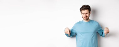 Şüpheci çocuk, beyaz arka planda duran, kötü tanıtım teklifine bakan, ve hayal kırıklığına uğramış,.