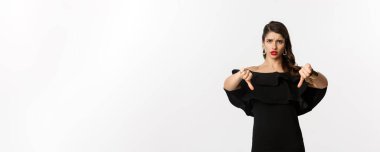 Moda ve güzellik. Siyah elbiseli, hayal kırıklığına uğramış ve üzgün bir kadın. Başparmaklarını göstermiyor. Kötü bir şeyden hoşlanmıyor..