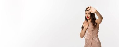 Kutlama, tatil ve parti kavramı. Genç bir kadın kendini rahatsız hissediyor, dur hareketi yapıyor, ellerini kaldırarak kendini savunuyor, elbise giyiyor, beyaz bir altyapısı var..