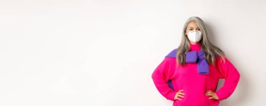 Covid, salgın hastalık ve sosyalleşme konsepti. Solunum cihazındaki kendinden emin ve neşeli Asyalı son sınıf öğrencisi. Neşeli görünüyor, gülümsüyor ve el ele tutuşuyor..