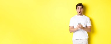 Adam şaşırmış görünüyor, akıllı telefon kullanıyor, ağzını açıyor ve 