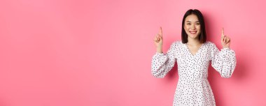 Güzel Koreli genç bir kadın duyuru yapıyor. Parmakla fotokopi makinesini işaret ediyor. Mutlu bir şekilde gülümsüyor..