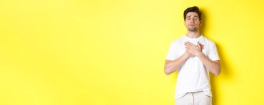 Romantik ve nostaljik bir adam, kalbi tutan, gözlerini kapatan ve sarı arka planda duran bir şeyi hatırlayan..