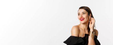 Moda ve güzellik konsepti. Kırmızı dudaklı, siyah elbiseli zarif esmer kadının yakın çekimi. Kahkahalar atıp duran, beyaz arka planda duran..