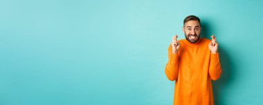 Endişeli bir adam dilek diliyor, bir şeyler umuyor, şans diliyor, turkuaz arka planda gergin duruyor..