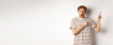 Kıvırcık saçlı heyecanlı bir adam tanıtım teklifi sunuyor ve şaşırmış görünüyor, sağ üst köşedeki logoyu işaret ediyor, beyaz arka plan..