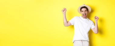 Turizm ve yaşam tarzı kavramı. Mutlu turist kutlaması, tatilde sevinç, sarı arka planda durmak.