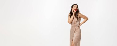 Parti ve kutlama konsepti. Gece elbisesi giymiş, Noel hediyelerinin yanında duran, beyaz arka planda duran, şaşırmış görünen zarif bir kadın..