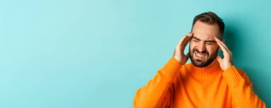 Sorunlu adamın baş ağrısı, buruşukluk ve baş ağrısı, migren ağrısı, açık mavi arka planda durması..