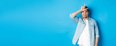 Kaybettiği için alay eden kaba bir adam. Alnında ezik işareti olan ve mavi arka plana karşı duran biri..