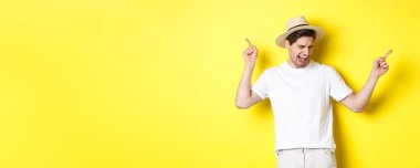 Turizm ve yaşam tarzı kavramı. Mutlu adam tatilde, turist sarı arka planda dans ediyor..