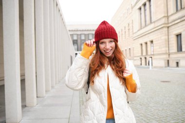 Happy redhead girl, tourist going around town, exploring sighsteeing places in city, backpacking around europe, enjoys travelling.