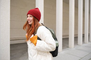 Happy redhead girl, tourist going around town, exploring sighsteeing places in city, backpacking around europe, enjoys travelling.