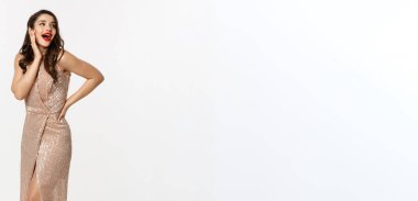 Parti ve kutlama konsepti. Gece elbisesi giymiş, Noel hediyelerinin yanında duran, beyaz arka planda duran, şaşırmış görünen zarif bir kadın..