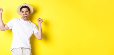 Turizm ve yaşam tarzı kavramı. Mutlu turist kutlaması, tatilde sevinç, sarı arka planda durmak.