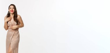 Parti ve kutlama konsepti. Zarif elbiseli, uzun boylu güzel bir kadın Noel hediyelerinin yanında duruyor, mutlu bir şekilde gülüyor, beyaz arka planda duruyor..