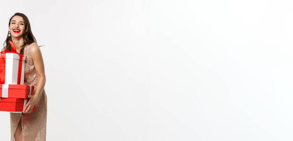 Концепция вечеринки и праздника. Полная длина привлекательной брюнетки в гламурном платье, держа рождественские подарки и смеясь счастливый, белый фон.