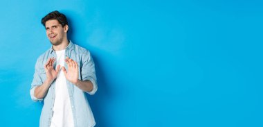 Memnuniyetsiz bir adam reddediyor, hayır diyor ve iğrenç bir şeyden korkup mavi arka planda duruyor..