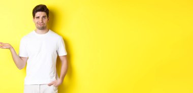 Kafası karışmış ve canı sıkkın adam elini kaldırsın, kafası karışmış, sarı arka plana karşı dursun. Boşluğu kopyala