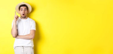 Hasır şapkalı genç adamın portresi bir fikir öne sürüyor, parmak Eureka işaretini kaldırıyor, telkinlerde bulunuyor, sarı arka planda duruyor..