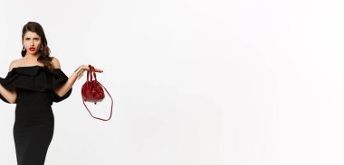 Güzellik ve moda konsepti. Hayal kırıklığına uğramış, kafası karışmış, kafası karışmış, kafası karışmış, şaşkın, parti elbisesi ve yüksek topuklu ayakkabılar giyen bir kadın..