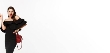 Güzellik ve moda konsepti. Cazibeli elbiseli, kırmızı dudaklı, parlak bir fikri olan, bir şey ima etmek için parmağını kaldıran bir sürü heyecanlı genç kadın. Beyaz arka plan..