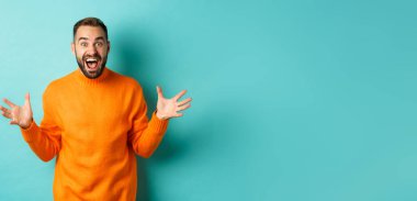 Mutlu ve heyecanlı adamın görüntüsü büyük haberleri duyurur, ellerini açar ve sevinç çığlıkları atar, neşe içinde, açık mavi arka planda durur..