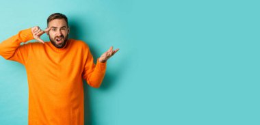 Kafasını işaret eden kızgın adam, sen deli misin? Açık mavi arka planda dikilen birini azarlıyor musun? Boşluğu kopyala