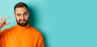 Kafkasyalı adamın küçük ya da küçük parmakları olan, açık mavi arka planda hayal kırıklığına uğramış bir görüntüsü..