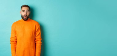 Şok olmuş ve kafası karışmış bir adam, tanıtım teklifine hayranlıkla bakıyor, turkuaz arka planda fotokopi alanının yanında duruyor..